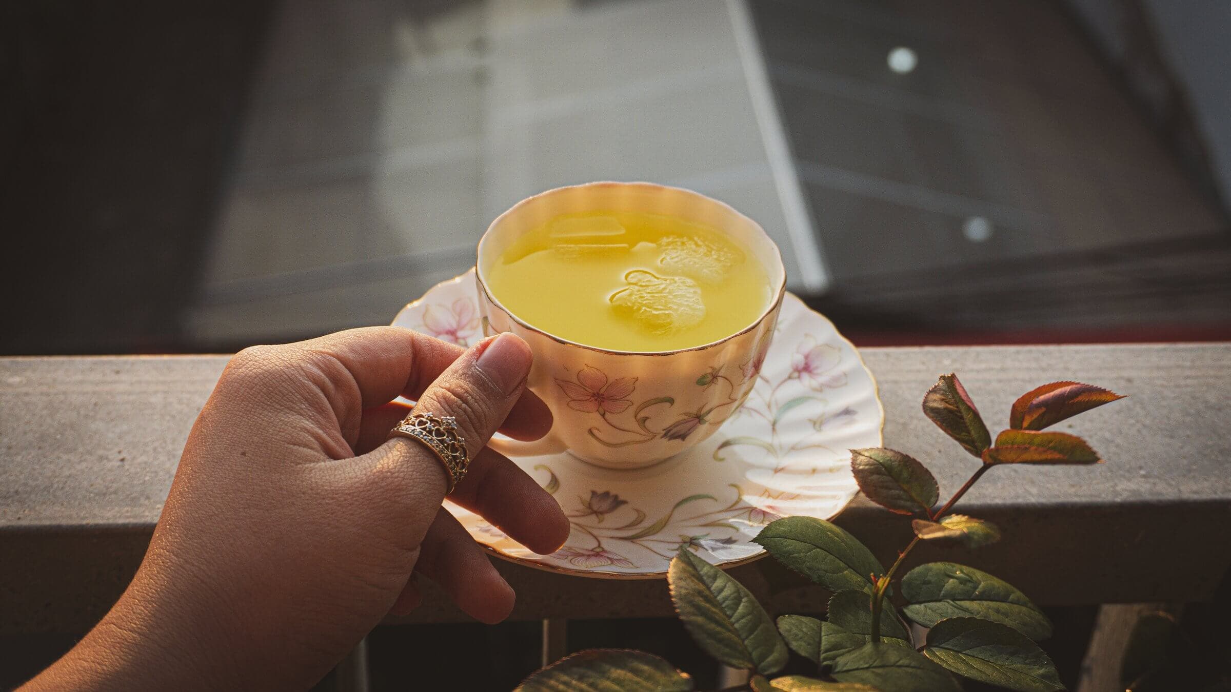 Hand holding cup of tea.