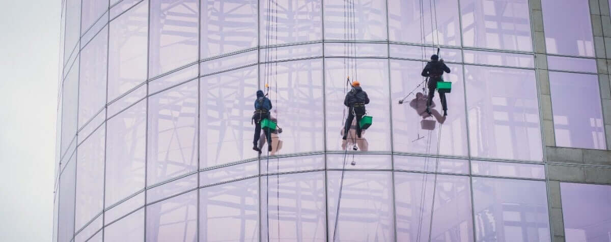 High-rise window cleaner on rope descent system cleaning a glass facade