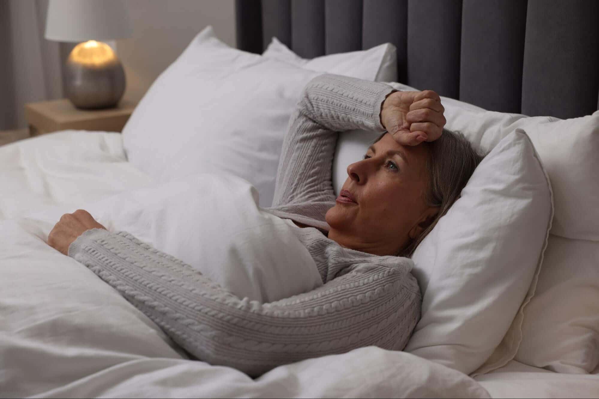 Woman that's stressing in her bed because she is hot and can't fall asleep