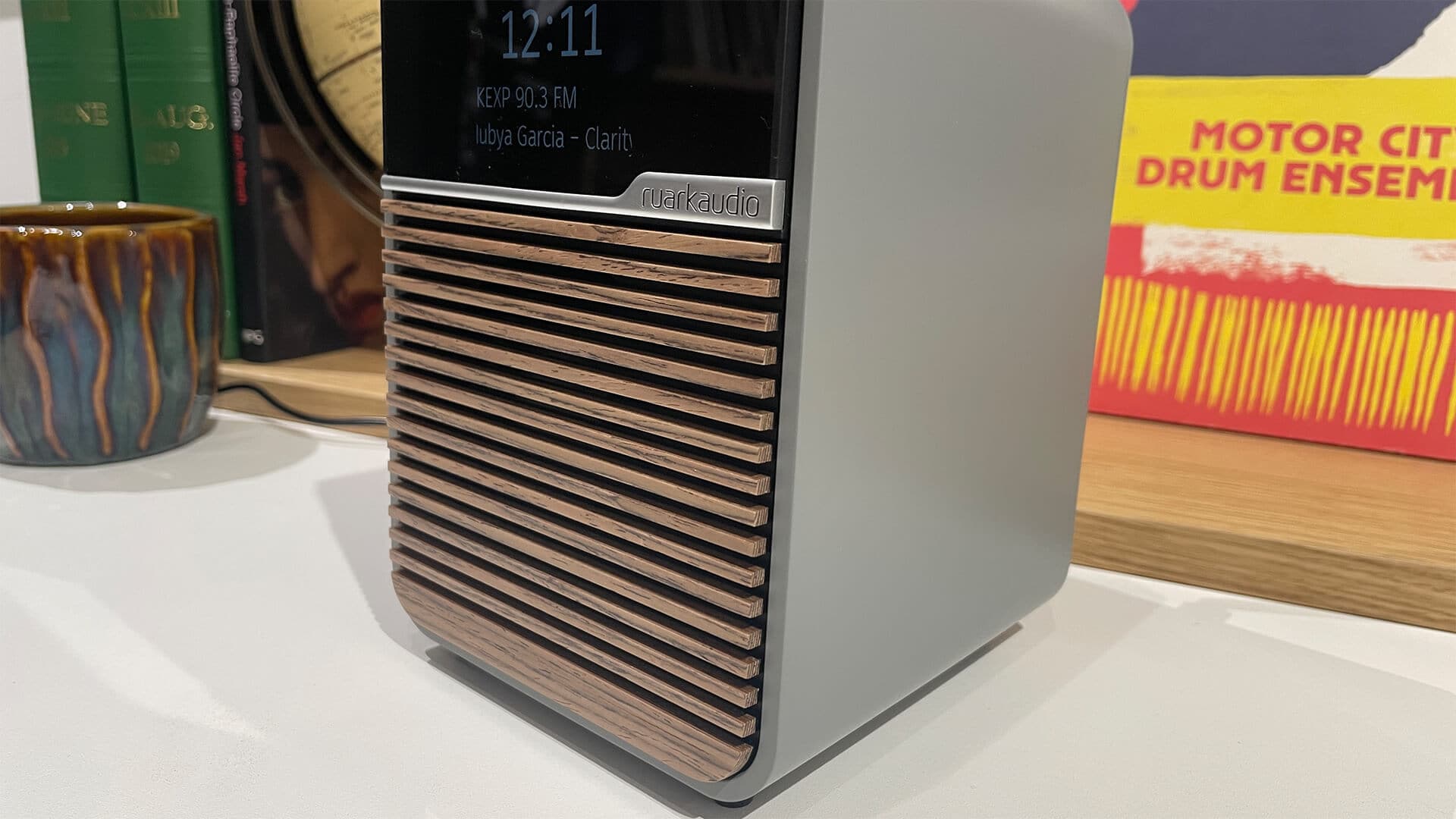 Ruark Audio R1S on a white shelf showcasing its slatted wooden front