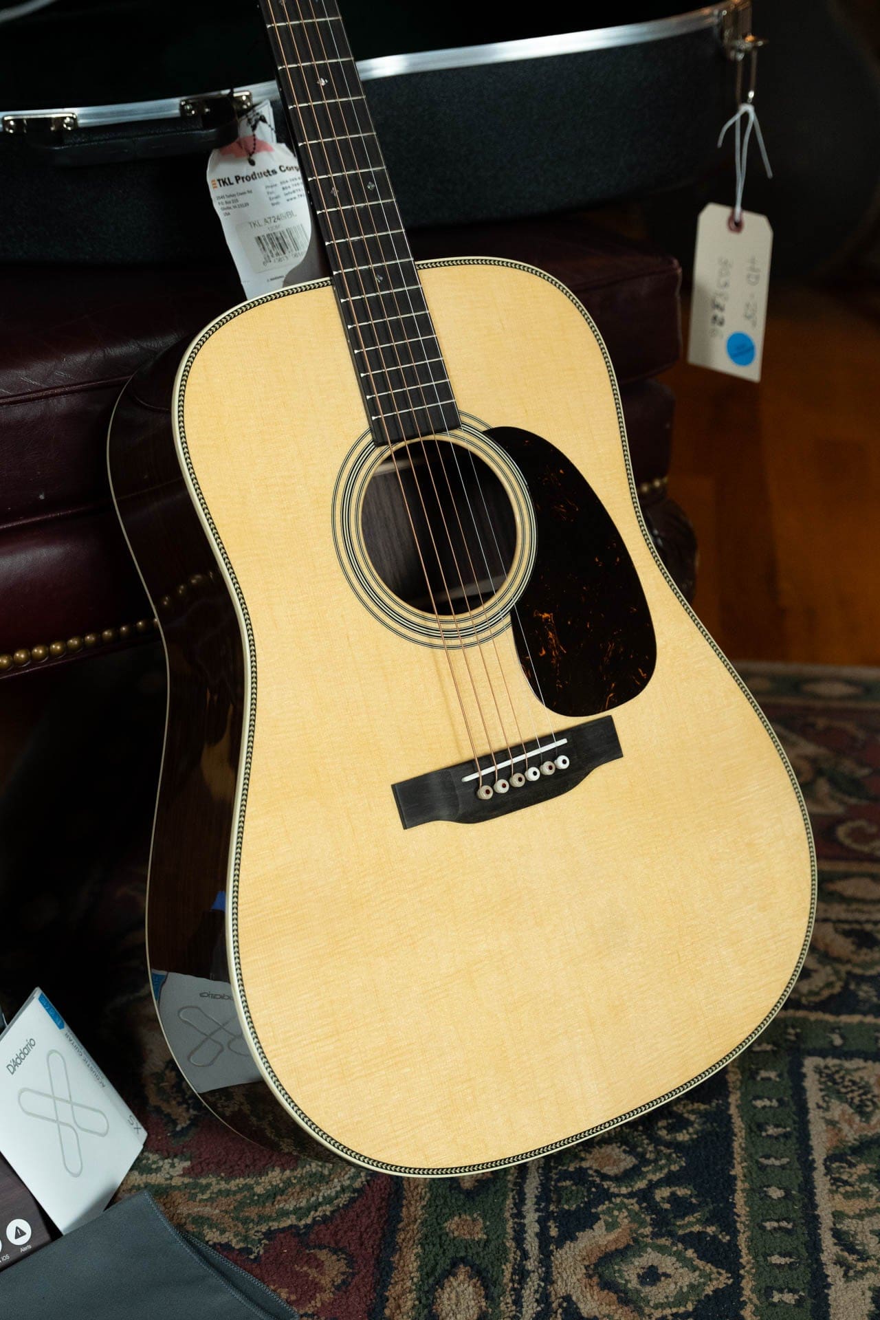 Martin HD-28 dreadnought with herringbone trim and dark pickguard standing on a patterned rug in our showroom