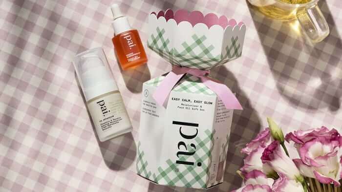 Pai Skincare spring gift set with Rosehip BioRegenerate Oil and Instant Calm Redness Serum displayed on gingham fabric with tea and flowers