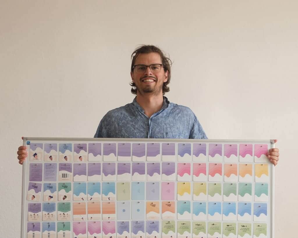 Founder Roel Vogels holding a design board featuring the artwork and layouts for Scenario Cards.
